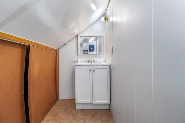 bathroom with lofted ceiling, tile patterned flooring, and vanity