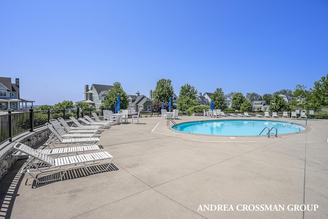 pool with a patio area, a residential view, and fence