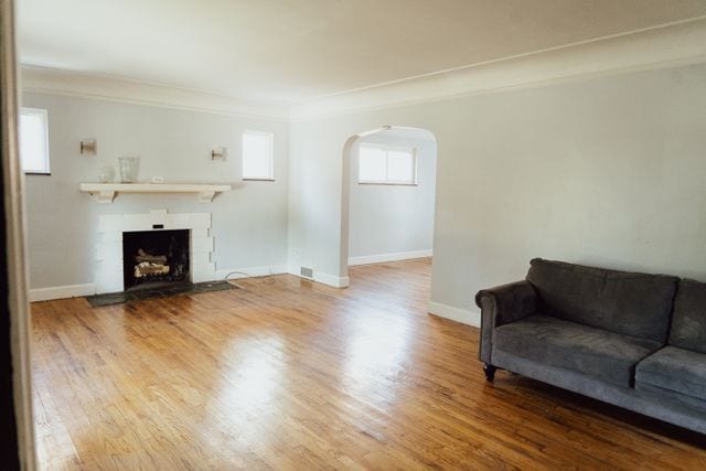 living room featuring baseboards, arched walkways, ornamental molding, wood finished floors, and a fireplace