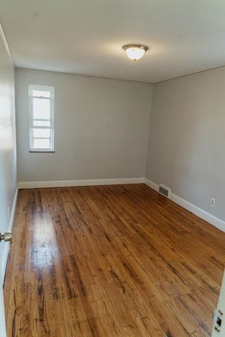 unfurnished room with visible vents, baseboards, and wood finished floors