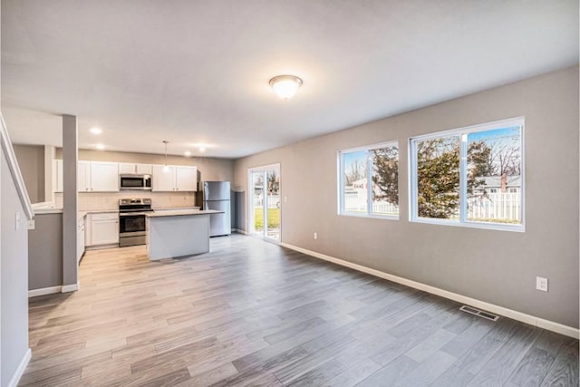 kitchen featuring visible vents, open floor plan, stainless steel appliances, light wood-style floors, and white cabinetry