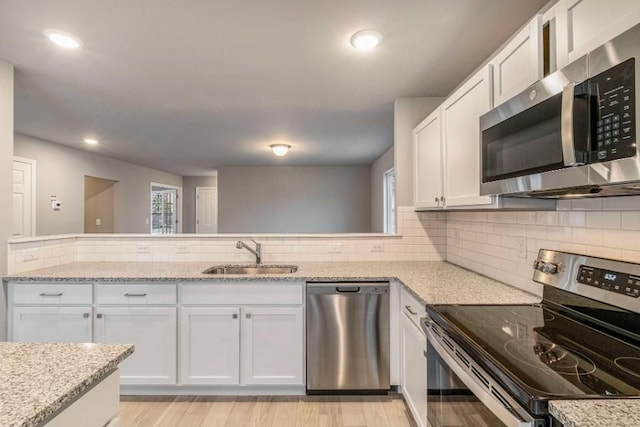 kitchen with stainless steel appliances, decorative backsplash, a sink, and white cabinets