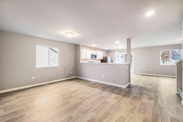 unfurnished living room featuring light wood finished floors, recessed lighting, and baseboards