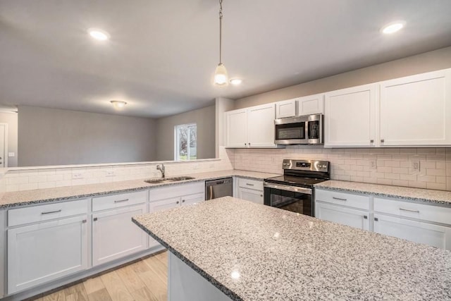 kitchen with stainless steel appliances, white cabinets, a sink, and backsplash