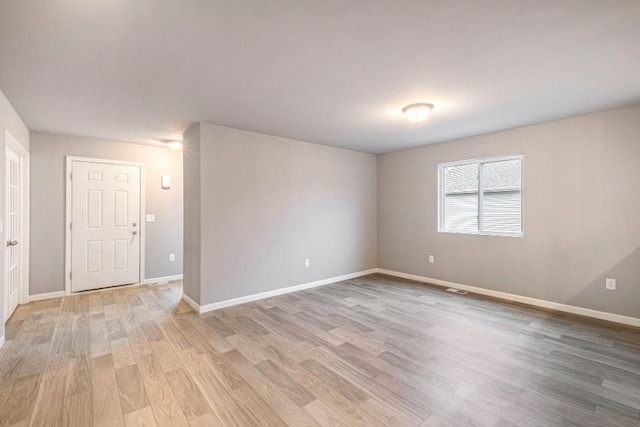 unfurnished room with light wood-type flooring and baseboards