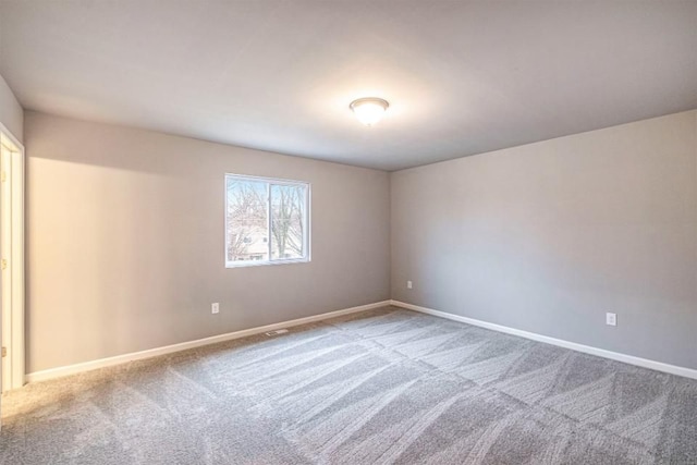 spare room featuring baseboards and carpet flooring