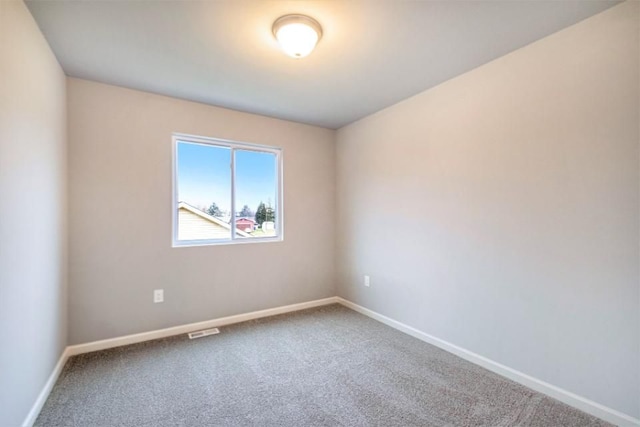 carpeted spare room featuring visible vents and baseboards