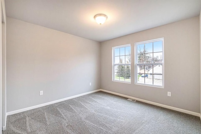 spare room featuring carpet flooring, visible vents, and baseboards