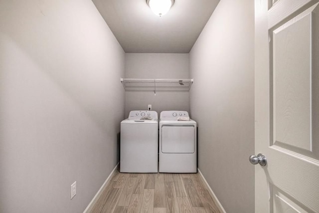 clothes washing area with laundry area, wood finished floors, washing machine and dryer, and baseboards