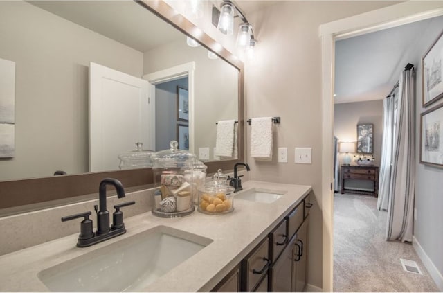 bathroom with double vanity, a sink, visible vents, and connected bathroom