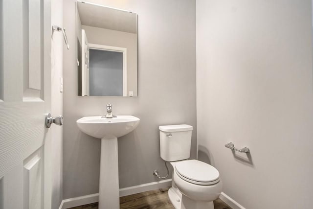 bathroom with baseboards, toilet, and wood finished floors