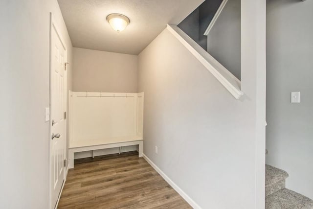 interior space featuring stairs, a textured ceiling, baseboards, and wood finished floors