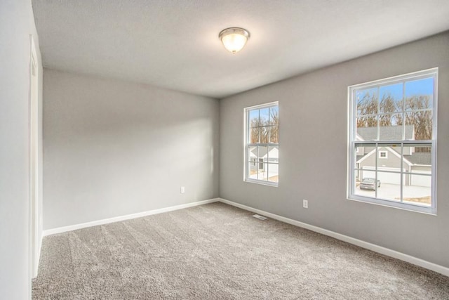 empty room featuring carpet and baseboards