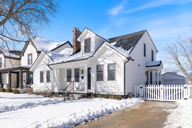 view of front of home with a porch, an outbuilding, and a chimney