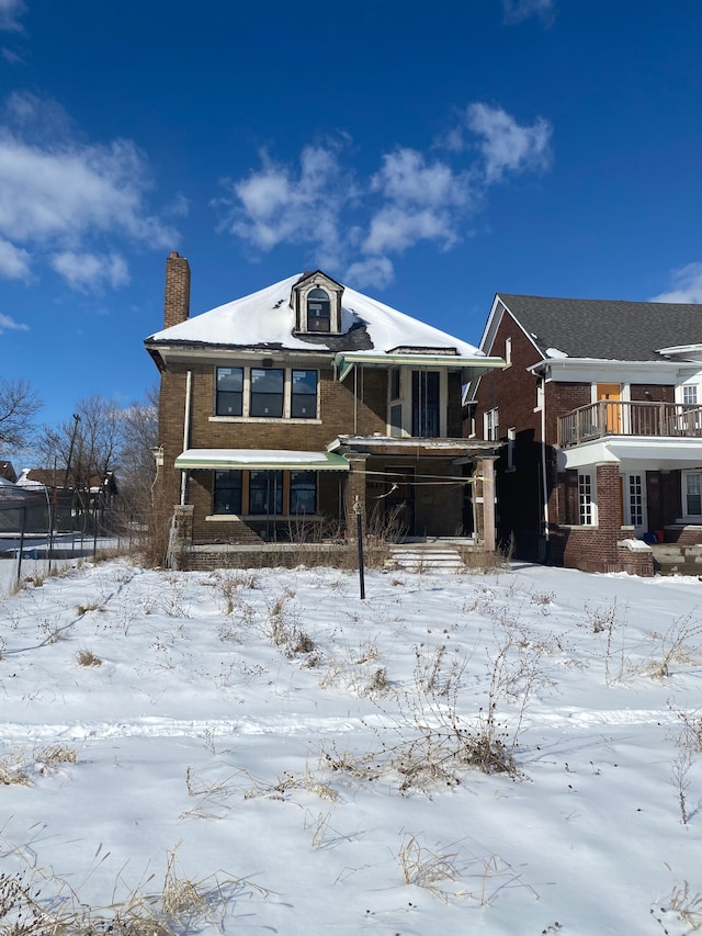 view of front of property with brick siding, a trampoline, and a chimney