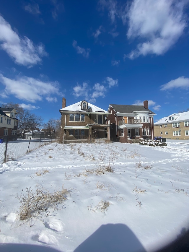 snow covered rear of property with a chimney