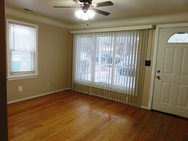 entrance foyer featuring baseboards, visible vents, a ceiling fan, ornamental molding, and wood finished floors