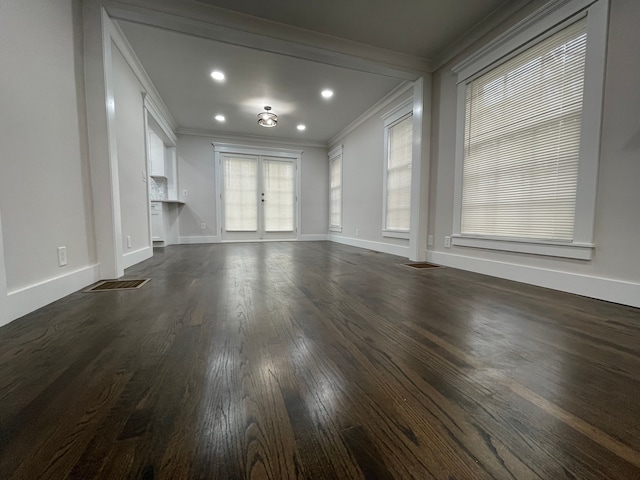 unfurnished living room featuring baseboards, ornamental molding, dark wood-style flooring, and french doors