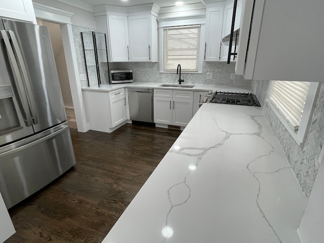 kitchen with a sink, white cabinetry, appliances with stainless steel finishes, light stone countertops, and dark wood finished floors