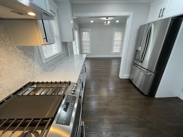 kitchen with light stone counters, dark wood finished floors, stainless steel appliances, white cabinets, and wall chimney range hood