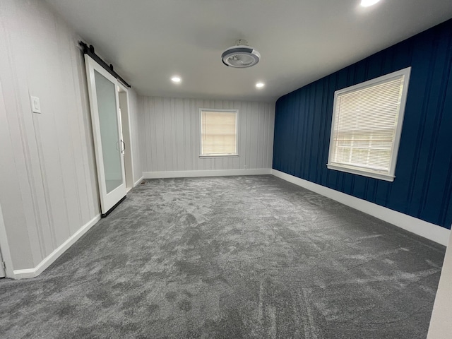 unfurnished bedroom featuring carpet, recessed lighting, baseboards, and a barn door