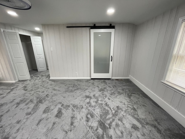 carpeted spare room featuring a barn door, visible vents, baseboards, and recessed lighting