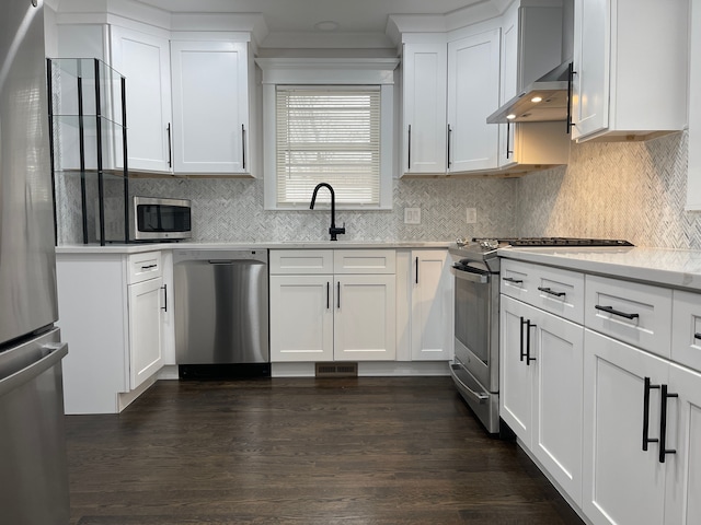 kitchen with light countertops, appliances with stainless steel finishes, wall chimney range hood, and white cabinets