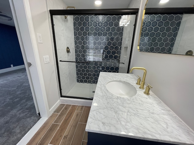 bathroom with baseboards, a shower stall, vanity, and wood tiled floor