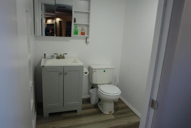 bathroom with baseboards, vanity, toilet, and wood finished floors