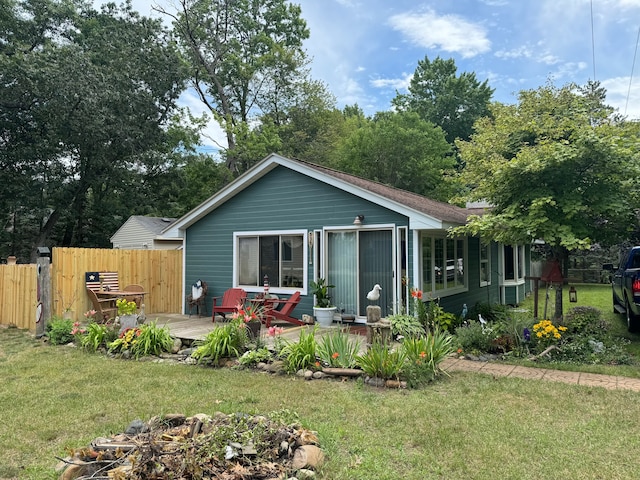 view of front of house with a deck, a front yard, and fence