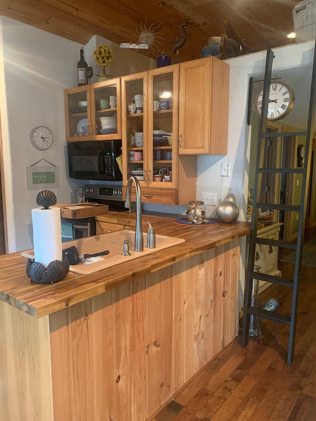 kitchen with light brown cabinets, wooden counters, glass insert cabinets, black microwave, and dark wood finished floors