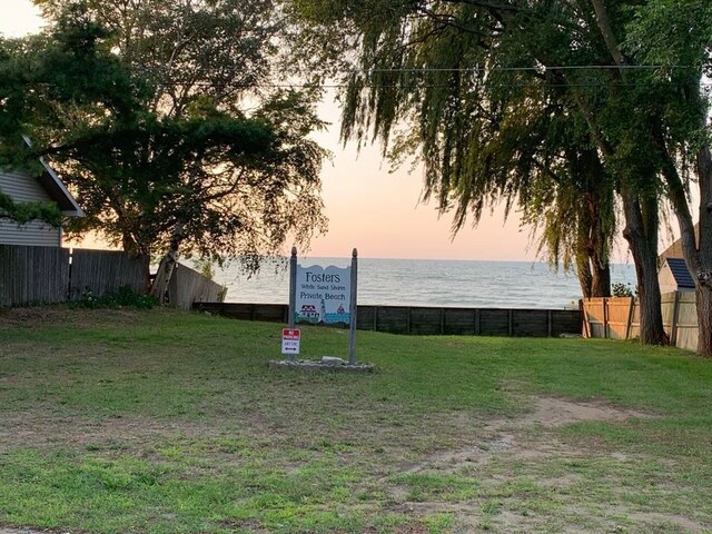 yard at dusk with fence and a water view