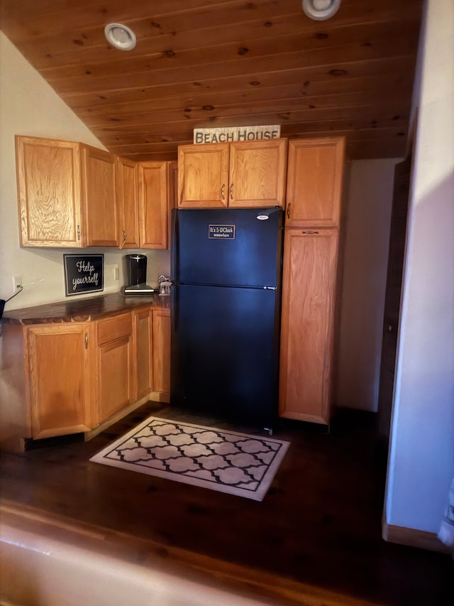 kitchen with dark countertops, wood ceiling, dark wood-style flooring, and freestanding refrigerator