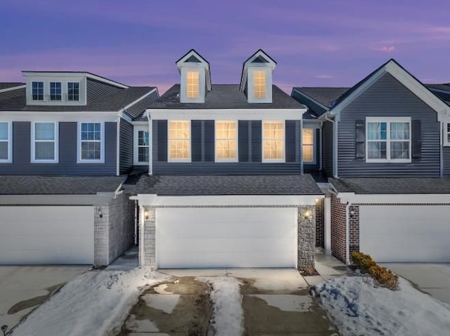 view of property featuring an attached garage, driveway, and a shingled roof