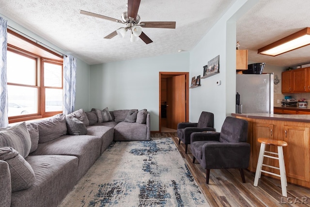 living room with lofted ceiling, ceiling fan, a textured ceiling, and wood finished floors