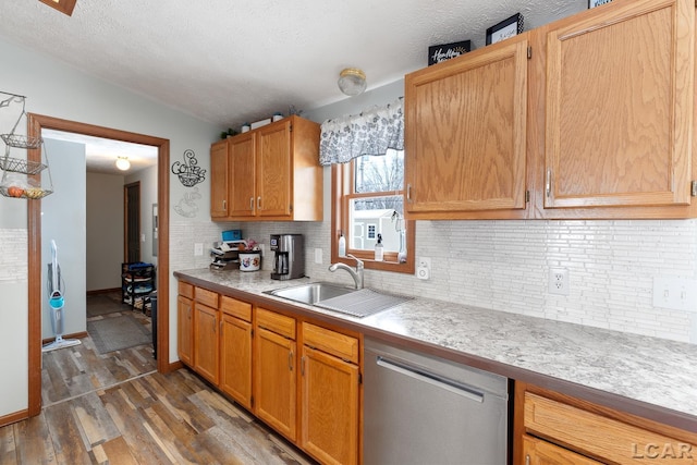 kitchen featuring dark wood-type flooring, a sink, light countertops, stainless steel dishwasher, and decorative backsplash