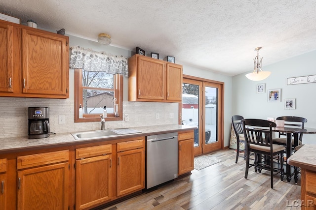 kitchen with dishwasher, light countertops, a healthy amount of sunlight, and pendant lighting