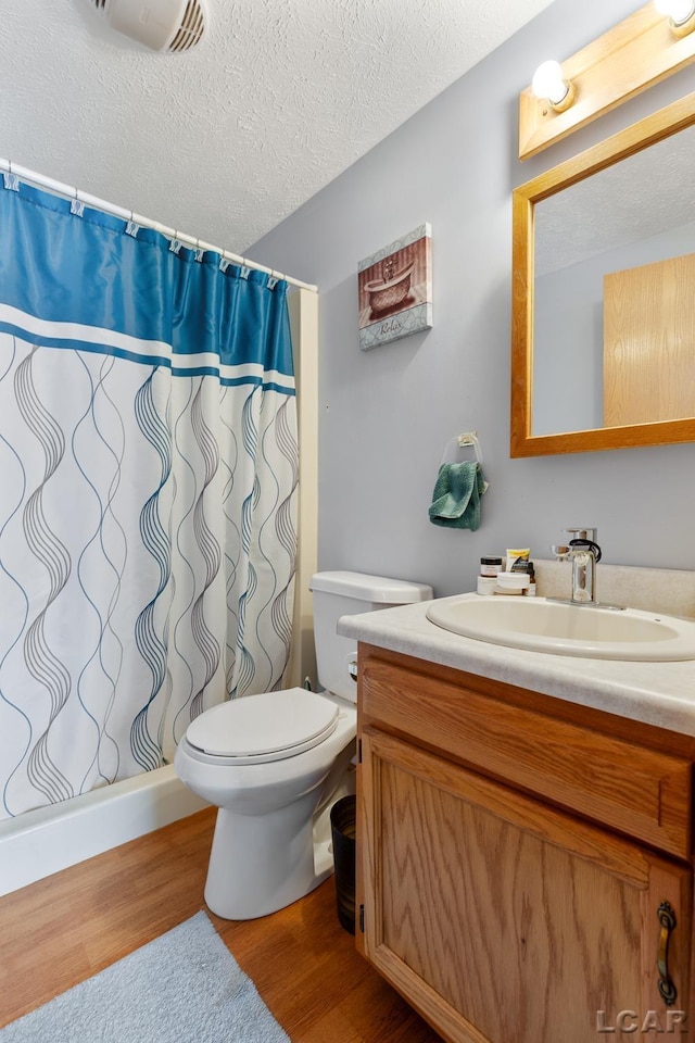 full bathroom featuring a textured ceiling, toilet, wood finished floors, vanity, and a shower with curtain