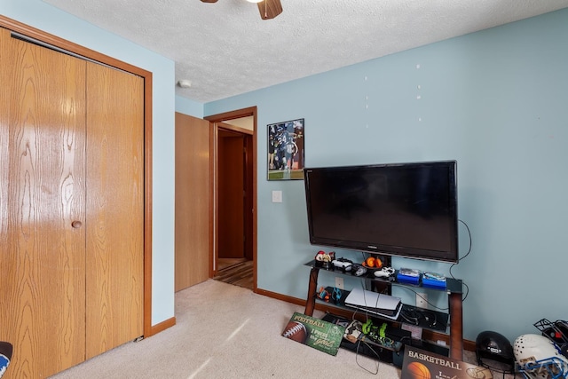 living room featuring baseboards, a ceiling fan, a textured ceiling, and light colored carpet