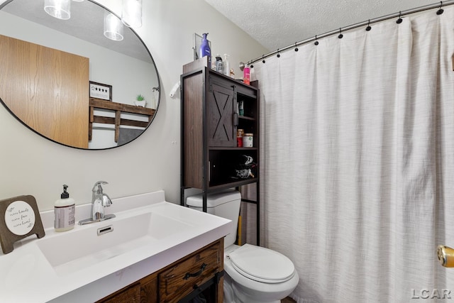 bathroom featuring toilet, a textured ceiling, and vanity