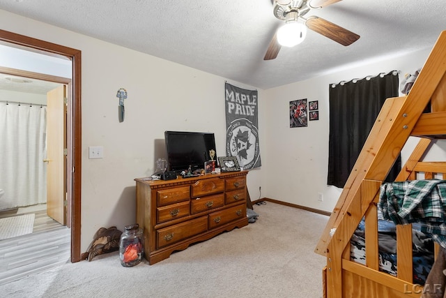 bedroom with light carpet, ceiling fan, a textured ceiling, and baseboards