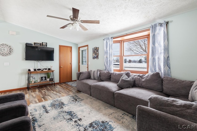 living room with light wood-style flooring, a ceiling fan, vaulted ceiling, and a textured ceiling