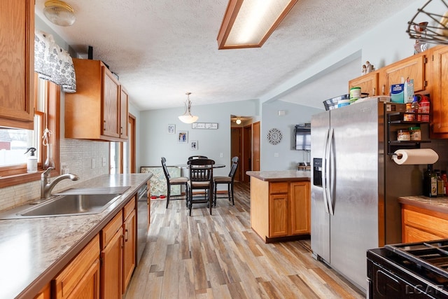 kitchen featuring lofted ceiling with beams, decorative light fixtures, stainless steel appliances, light countertops, and a sink