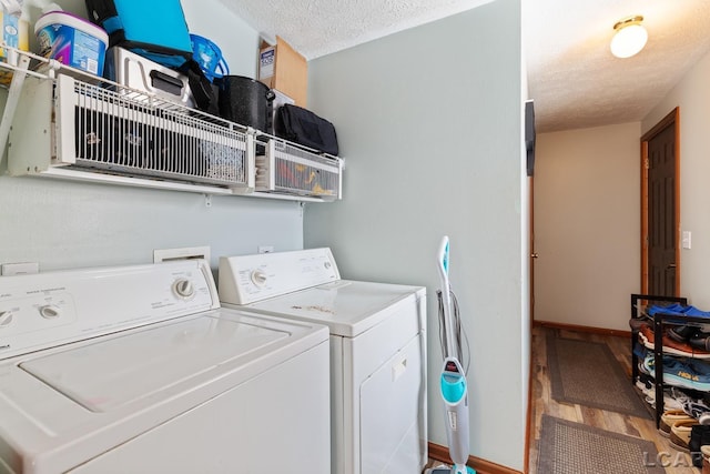 laundry area featuring a textured ceiling, wood finished floors, washer and dryer, laundry area, and baseboards