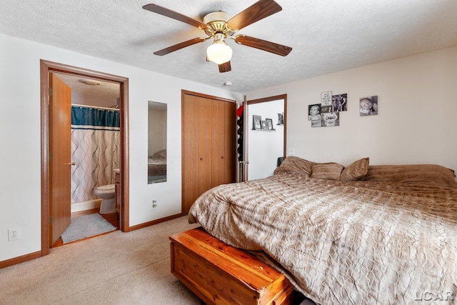 bedroom with a closet, light colored carpet, a textured ceiling, and baseboards