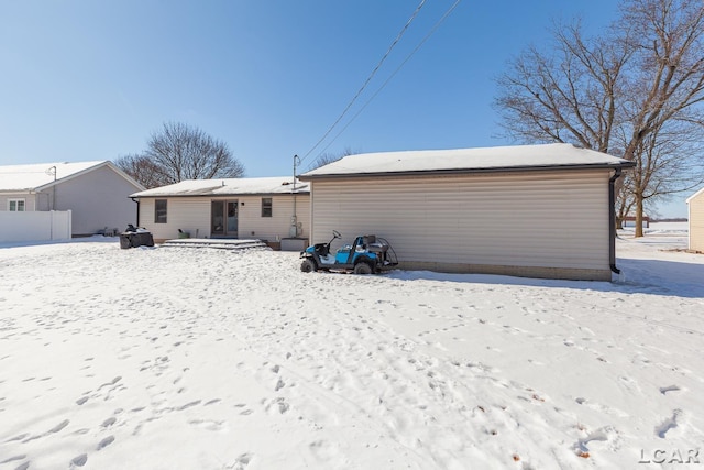 snow covered rear of property with a detached garage