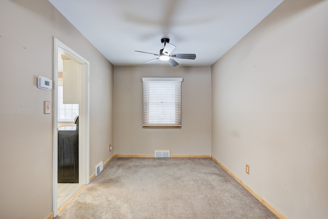 spare room featuring light carpet, a wealth of natural light, and visible vents