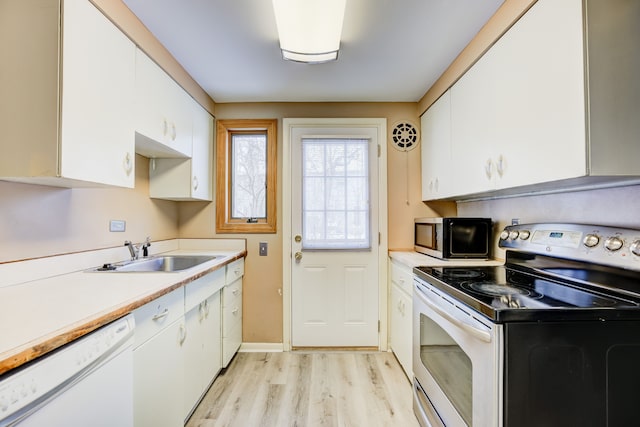 kitchen featuring stainless steel appliances, light countertops, a sink, and white cabinetry