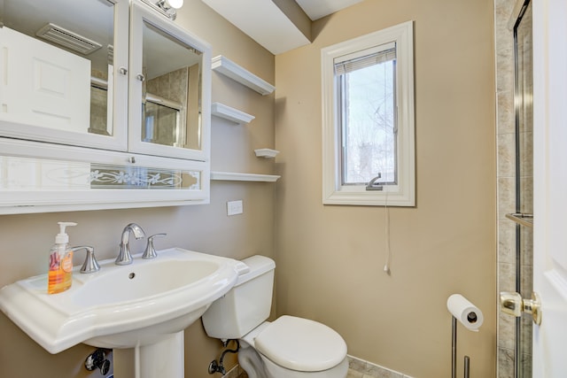 full bathroom with toilet, visible vents, a sink, and a shower with shower door