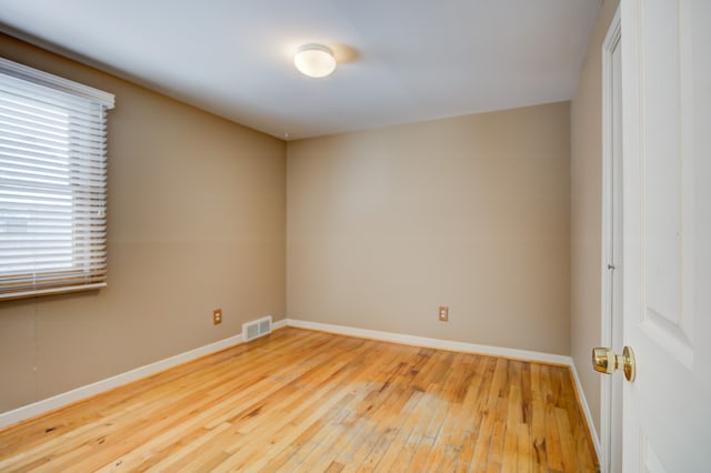 empty room with a healthy amount of sunlight, visible vents, baseboards, and wood finished floors